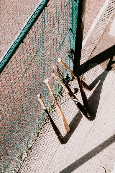 Baseball glove with ball on green grass, with blurred baseballs in the background.