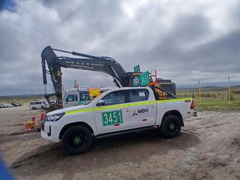 Camioneta blanca con el número de competición 2434 estacionada junto a una gran excavadora