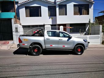 Camioneta plateada aparcada en una calle frente a casas blancas