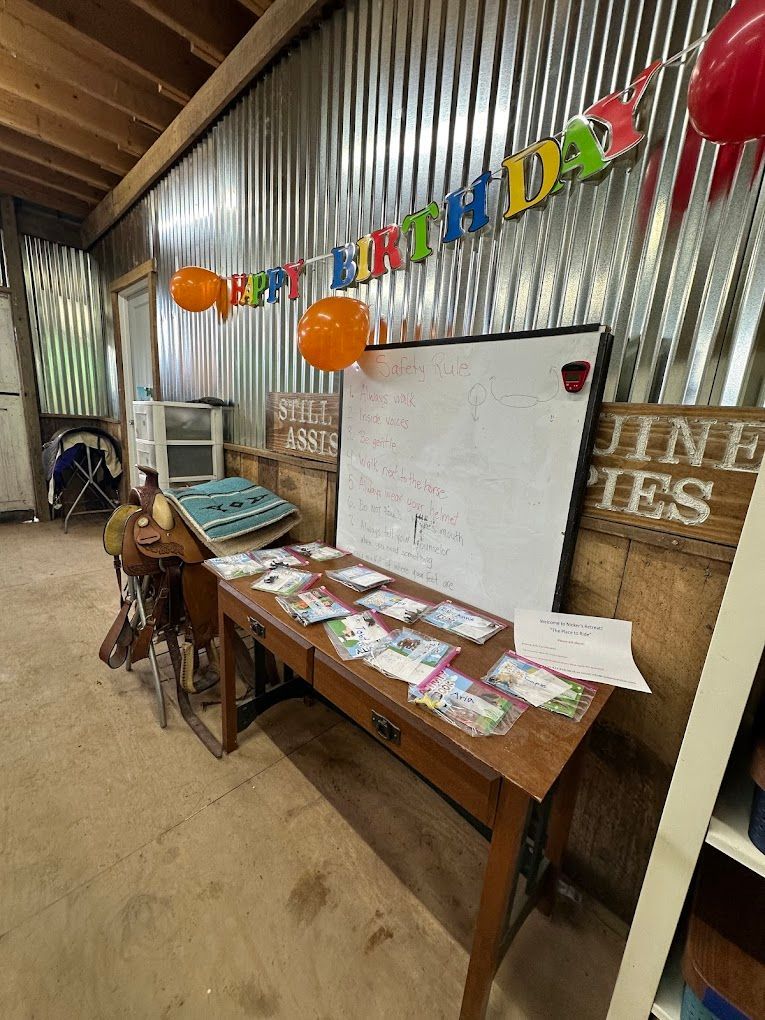 A room with a table , balloons , and a white board.