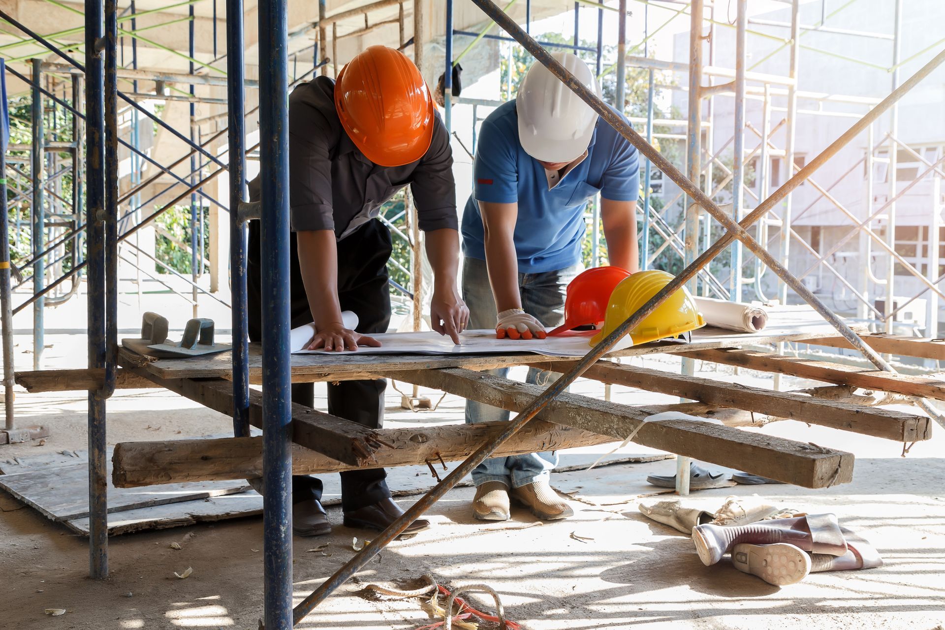 Two engineers review blueprints on-site, showcasing professional commercial construction services.