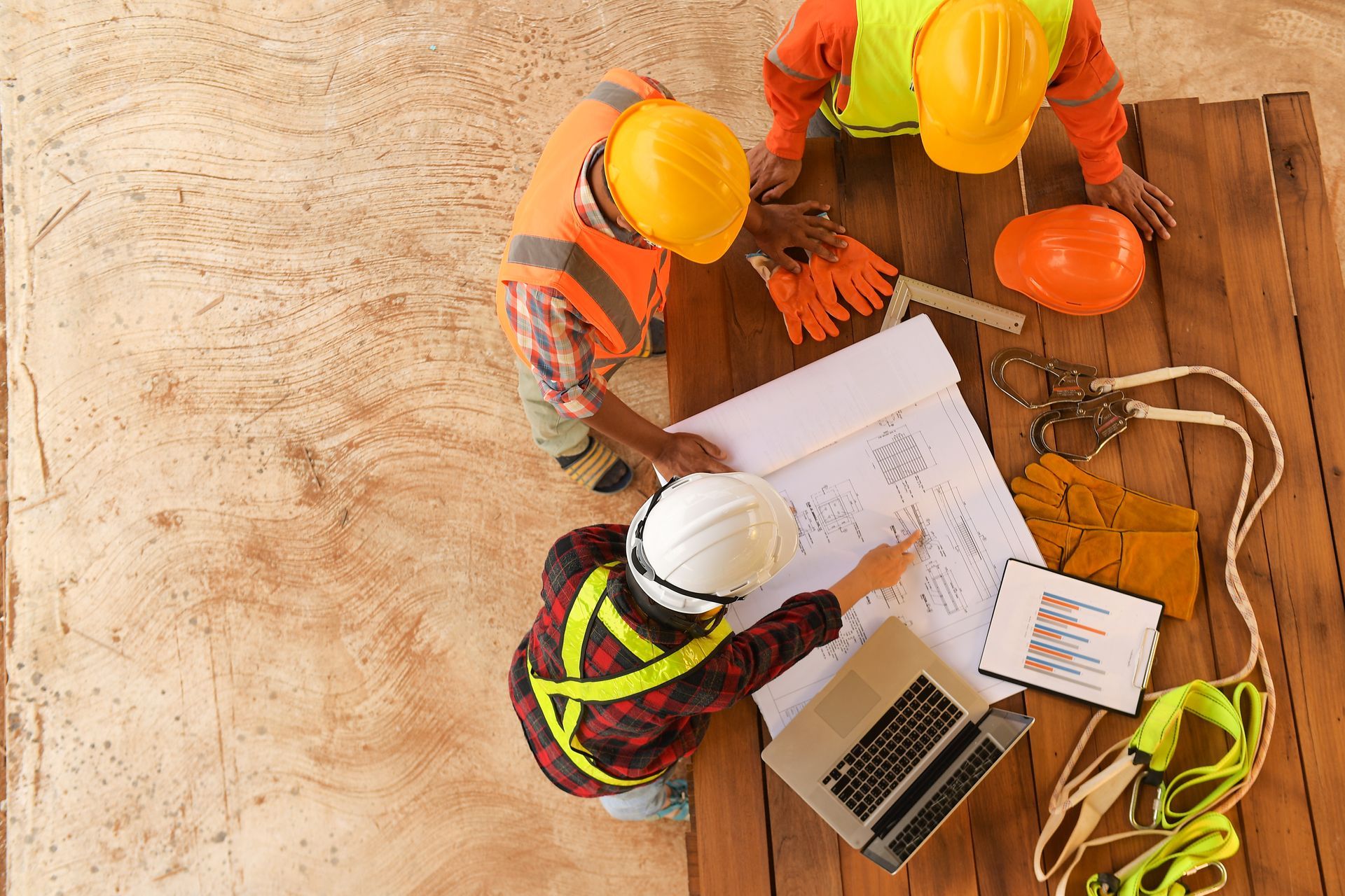 Construction workers reviewing blueprints and plans at an outdoor job site.