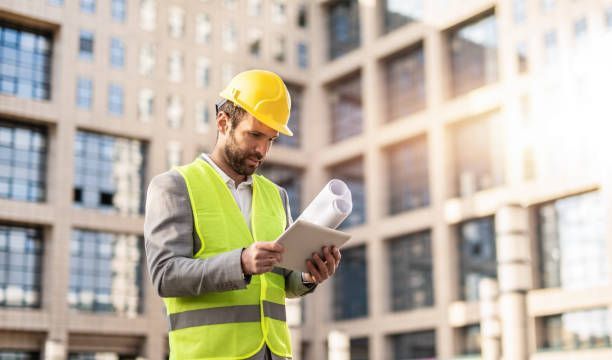 A building contractor is looking at a blueprint on a tablet.