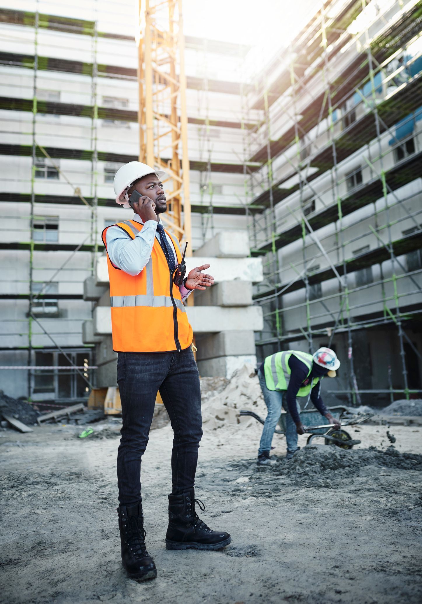 Man using a smartphone while working at a construction site. Man using a smartphone while working at a construction site.