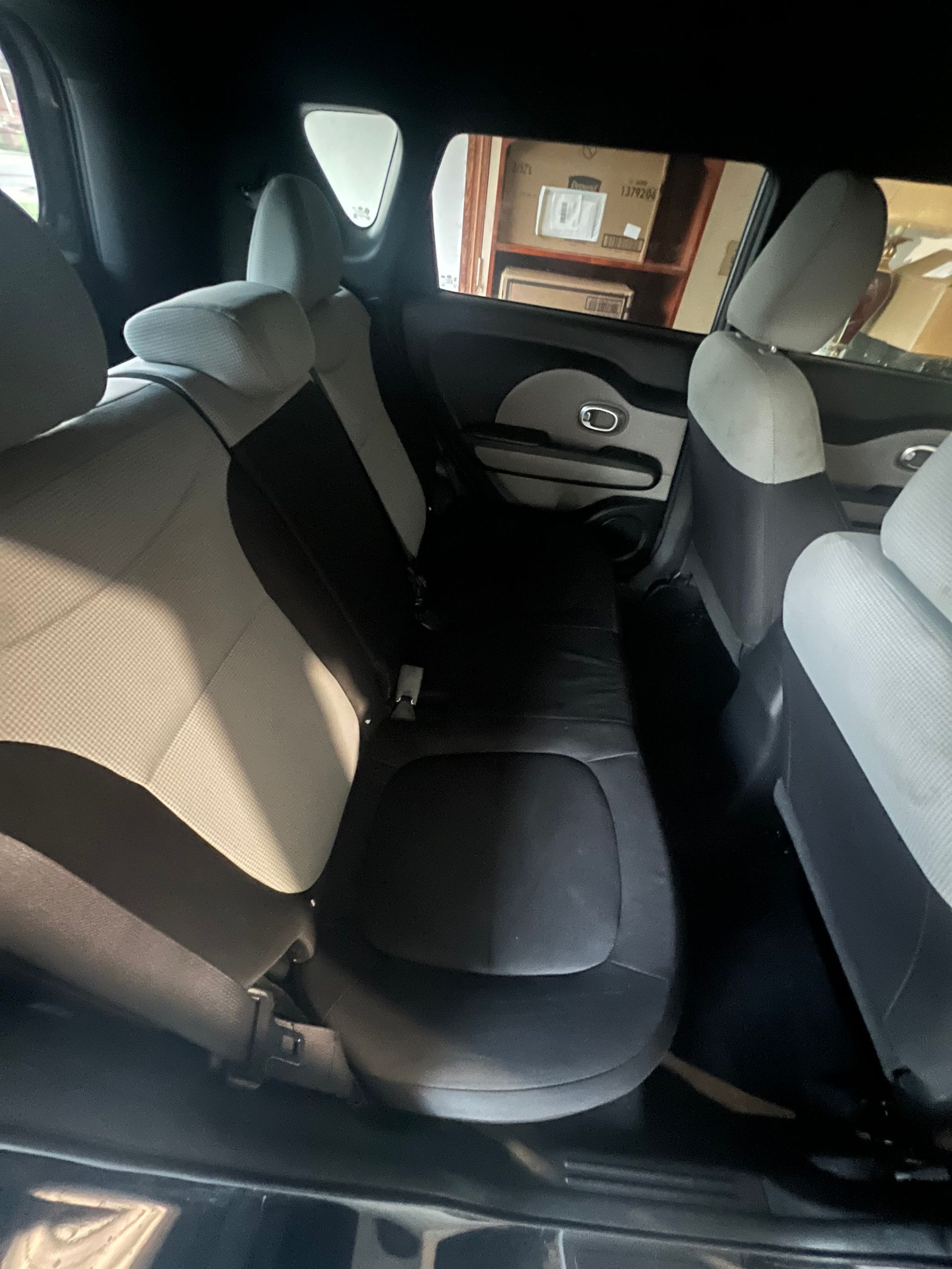 Back seat of a car with gray fabric seats and folded armrests, viewed from the rear.