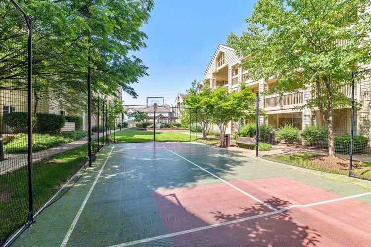 There is a basketball court in the middle of a park.