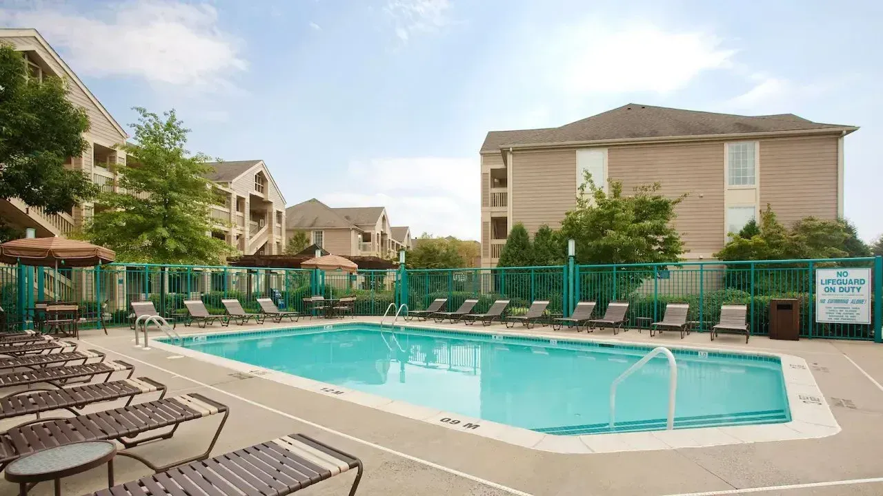 A large swimming pool surrounded by chairs and a building