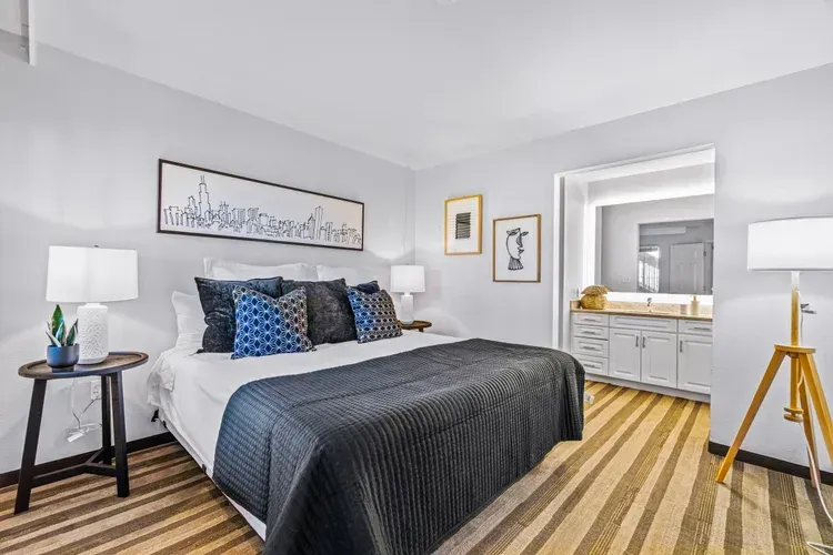 A bedroom with a large bed , lamps , and a bathroom.