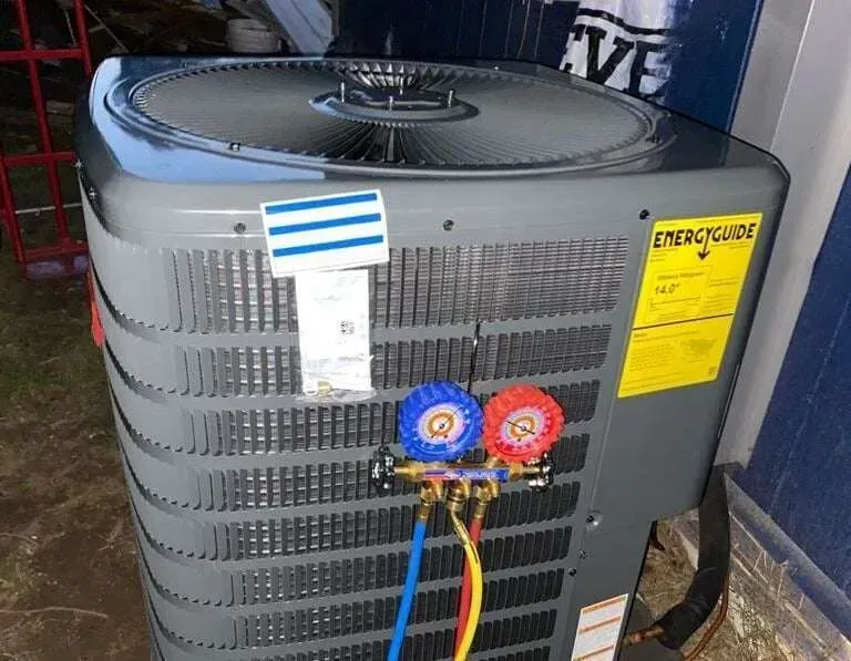 Outdoor air conditioner unit with gauges and colored hoses attached to the front