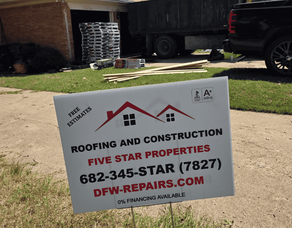 Yard sign for roofing and construction company, with phone number and website, in a driveway.
