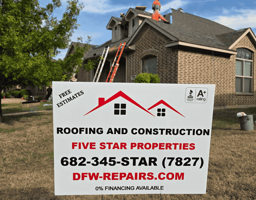 Roofing sign in front of a brick house, with workers on the roof and an extension ladder nearby.