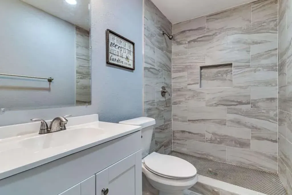 Modern bathroom with white vanity, mirror, and tiled shower/tub area