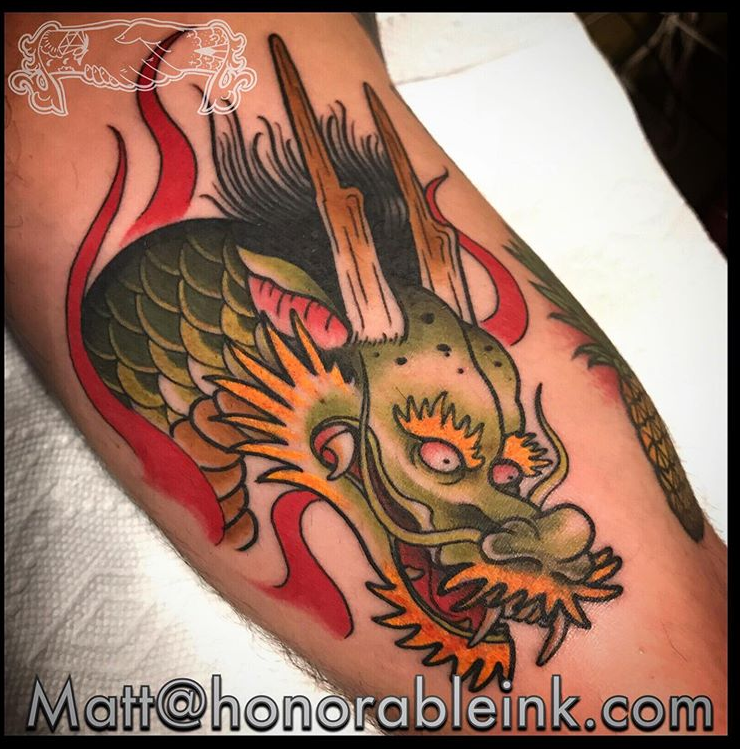 Colorful dragon tattoo on skin with red flames and green, orange, and black details