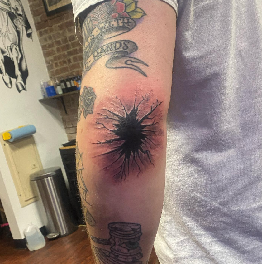 Forearm with a large black starburst tattoo and several smaller tattoos in a studio setting