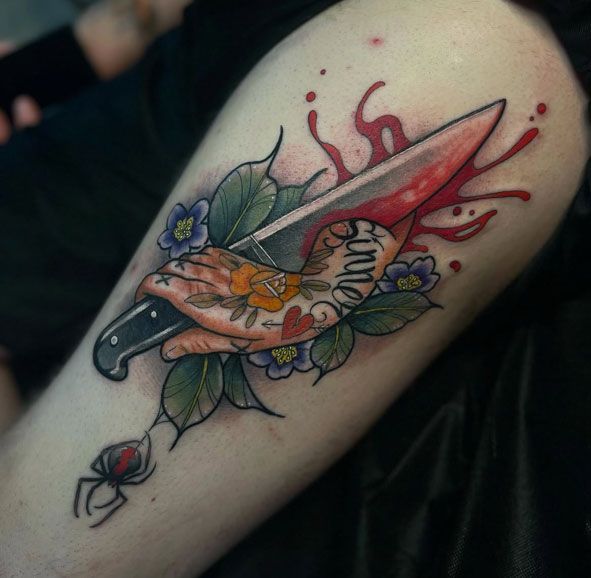 Tattoo of a red knife pierced through a heart with flowers and red splashes on skin