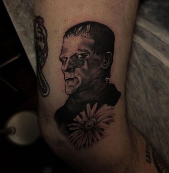 Black-and-gray tattoo of a man’s portrait with a flower on skin