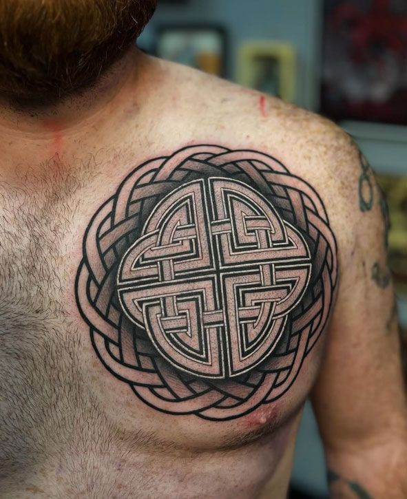 Close-up of a chest tattoo with a black Celtic knot design on light skin