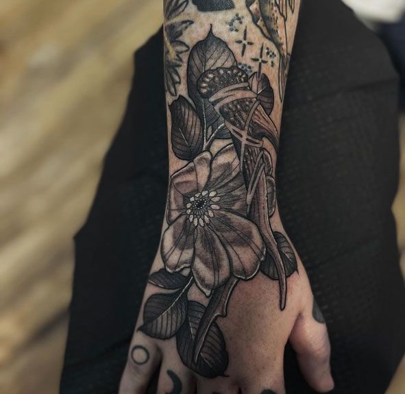 Tattooed hand and wrist with a detailed black floral tattoo in close-up