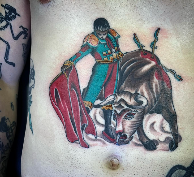 Colorful tattoo of a matador confronting a charging bull on a person's torso