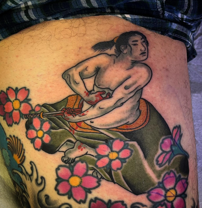 Tattoo of a seated figure in green pants among pink flowers on skin