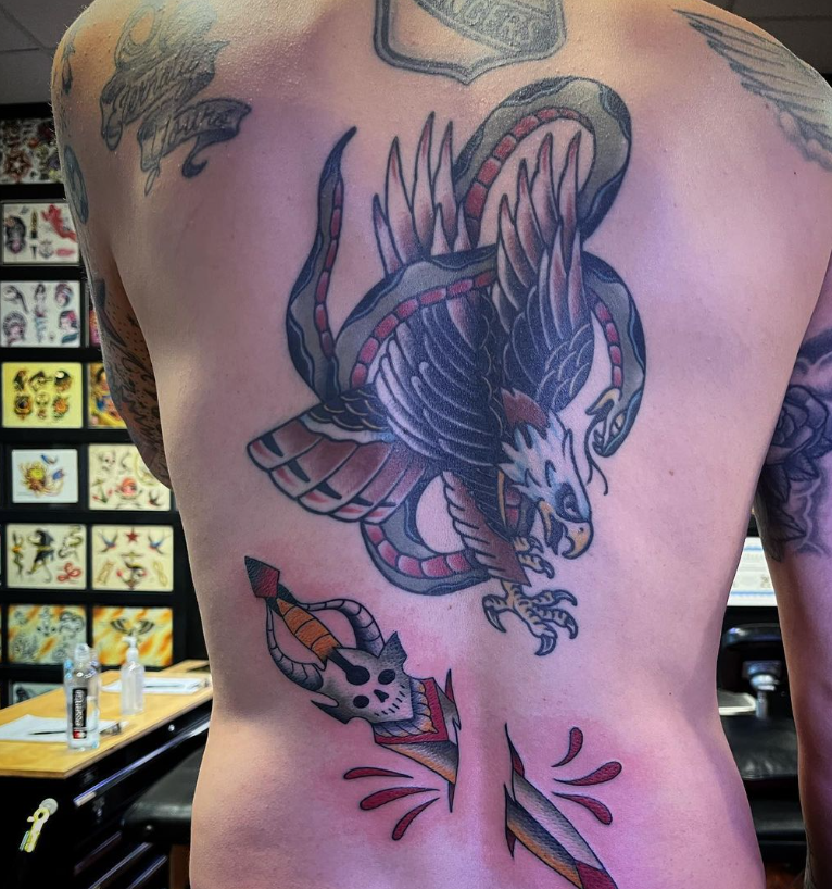 Tattooed back with a large colorful dragon tattoo in a tattoo studio