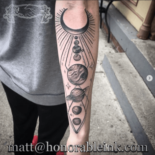 Arm with black crescent moon and planet tattoo design in black ink
