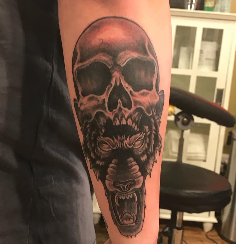 Black-and-gray skull tattoo on a forearm, with a second skull design below it.