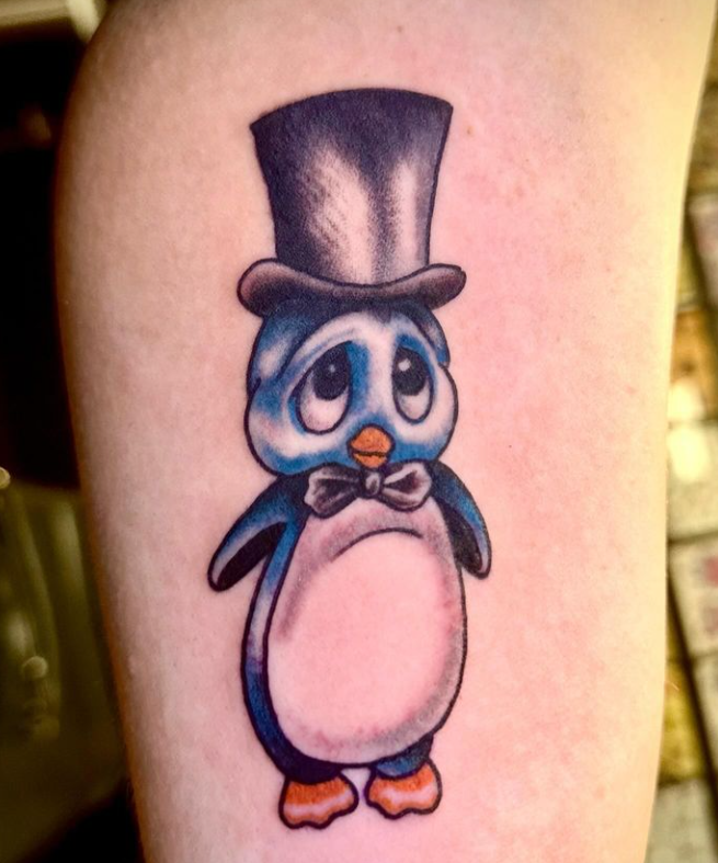 Cute blue-and-white cartoon penguin tattoo wearing a black top hat and bow tie