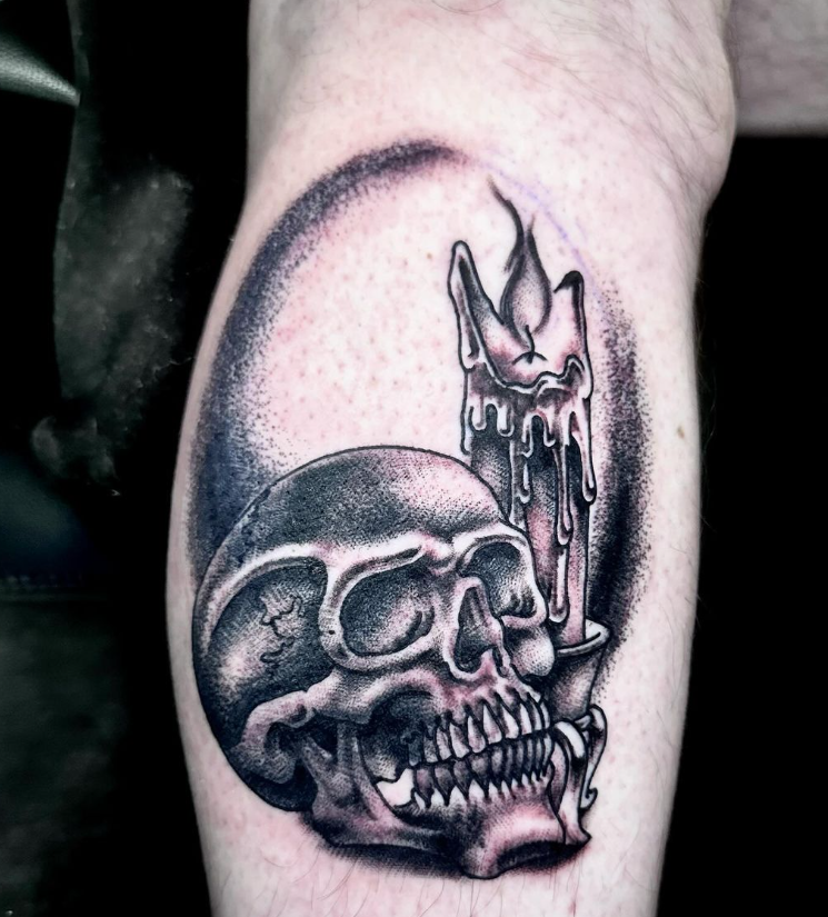 Black-and-gray skull tattoo with a candle on a forearm