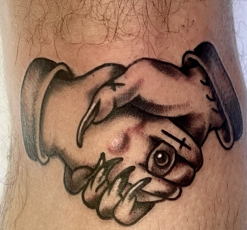 Black-and-gray tattoo of a stylized hand clutching a rope on skin