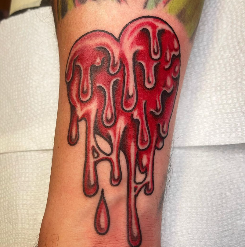 Close-up of a red dripping heart tattoo on skin