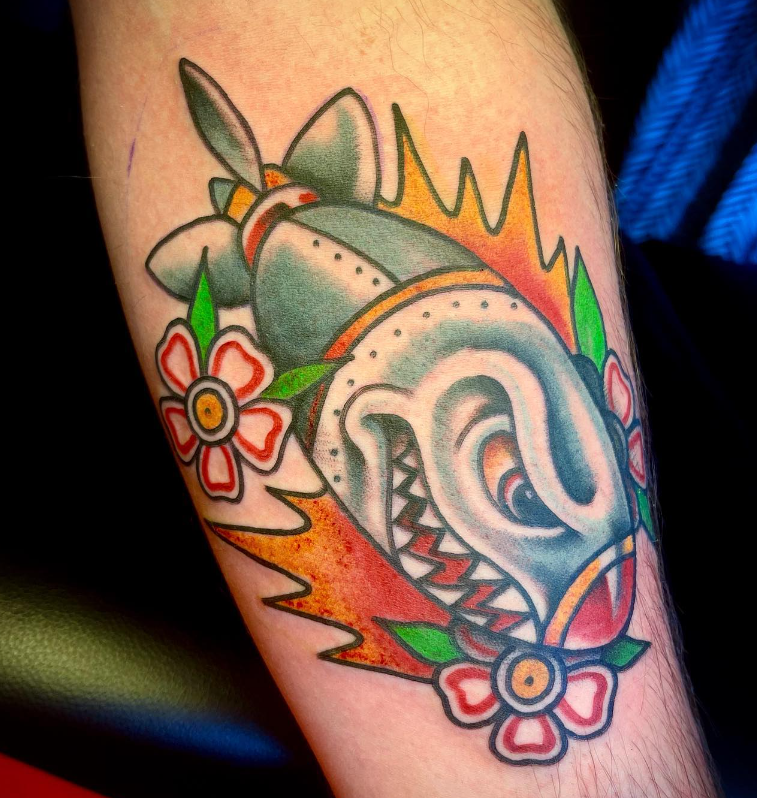 Colorful shark tattoo with flowers on skin, featuring green, orange, and red accents