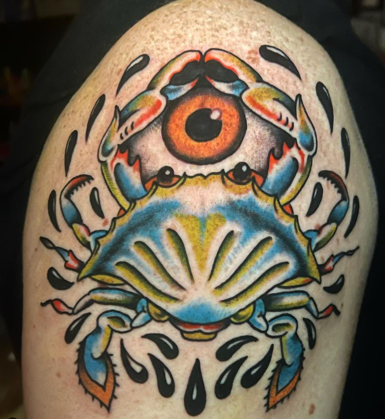 Colorful tattoo of a stylized crab with an eye and shell pattern on skin