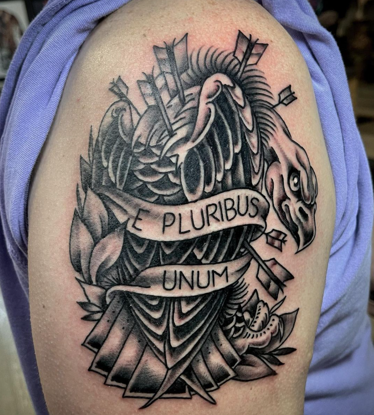 Black-and-gray tattoo of a bird with a banner reading