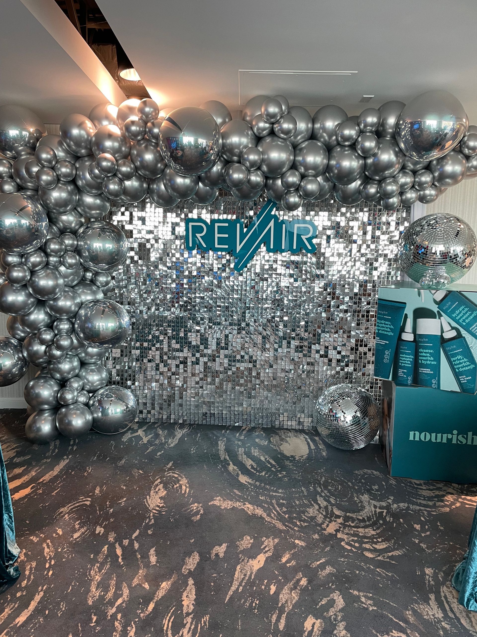 Silver chrome balloon installation across ceiling with mirrored sequin backdrop for corporate event