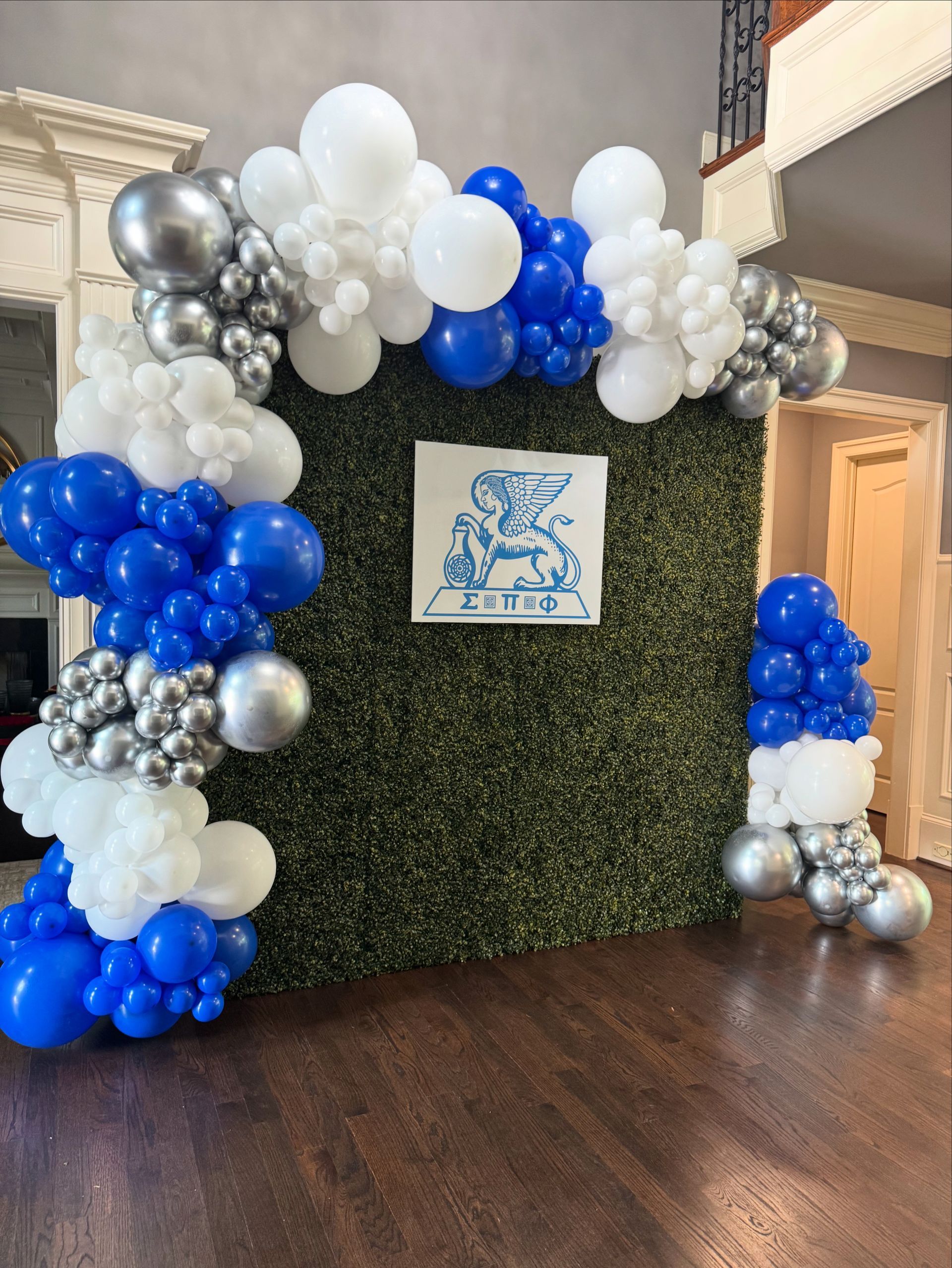 Blue, white, and silver balloon garland installed along an indoor wall and staircase landing