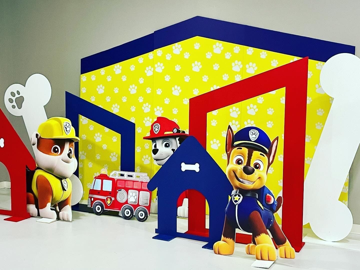 Paw Patrol themed birthday backdrop with character cutouts and colorful house set for kids party décor