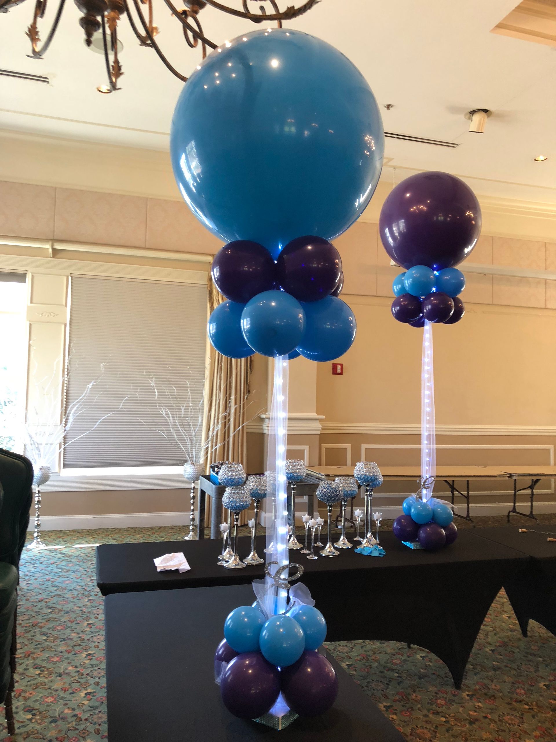 Large blue balloon columns with purple accents for entrance décor at party or corporate event