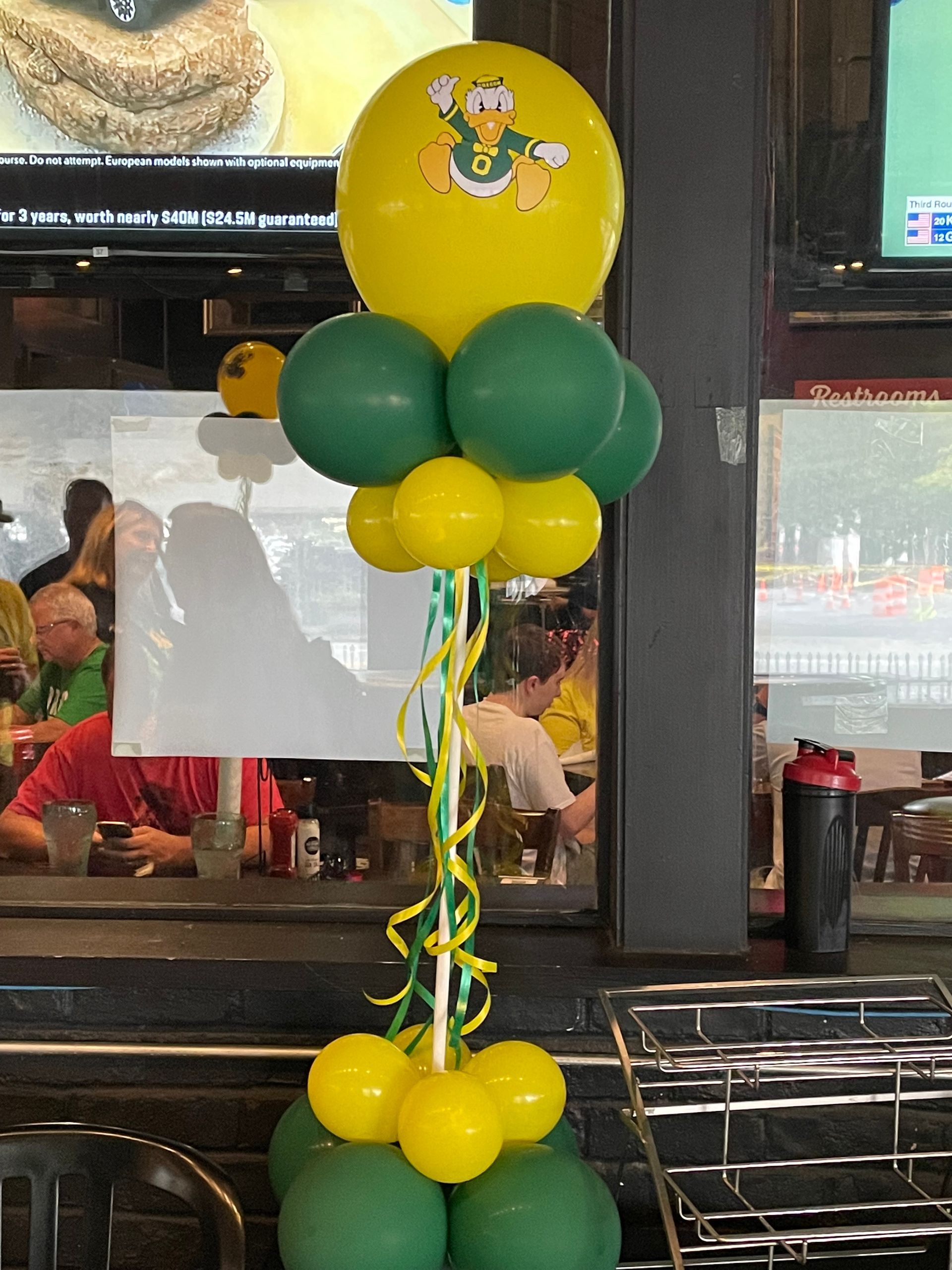 Green and yellow balloon stack with themed character topper for kids birthday party décor