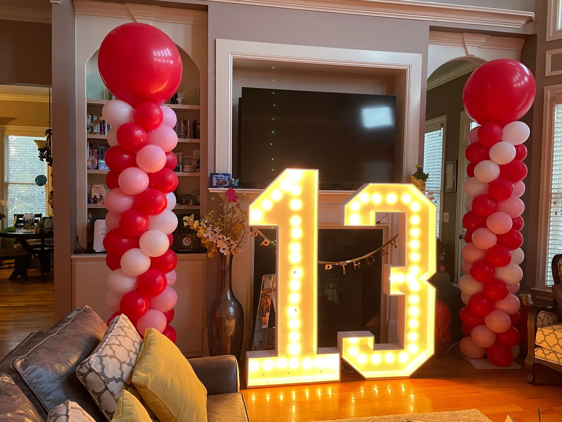 Red and pink balloon columns framing a marquee number 13 display for a birthday party