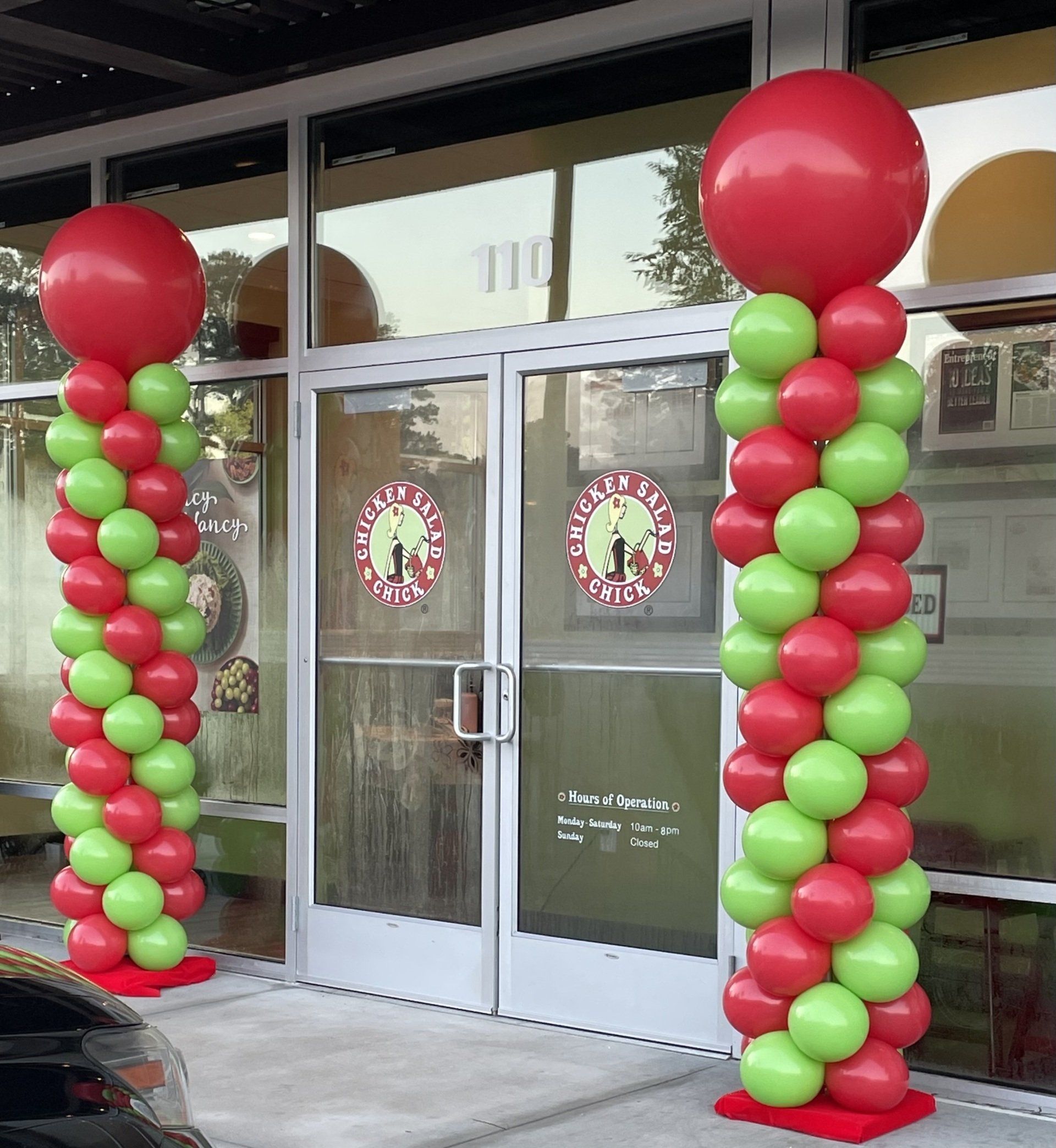 Red and green balloon columns framing a restaurant entrance for a holiday-themed event