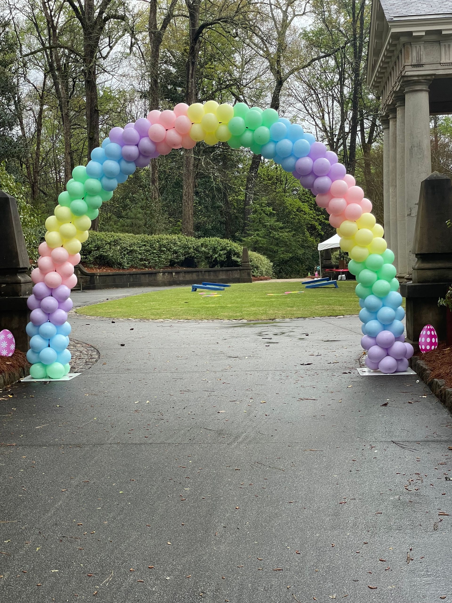 Pastel rainbow balloon arch outdoor garden setup for a party or celebration