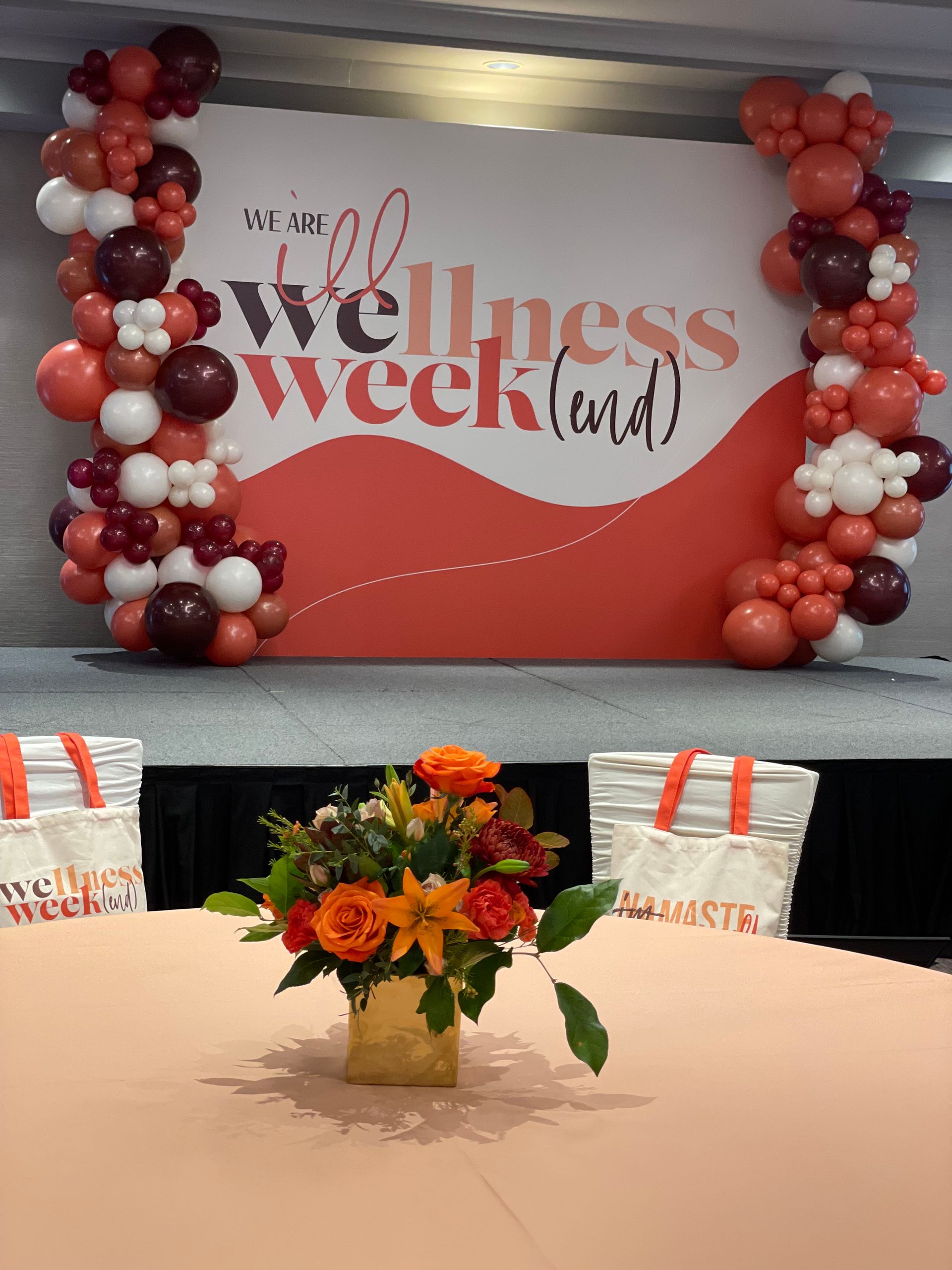Terracotta and white balloon columns framing wellness event backdrop for conference or company celebration
