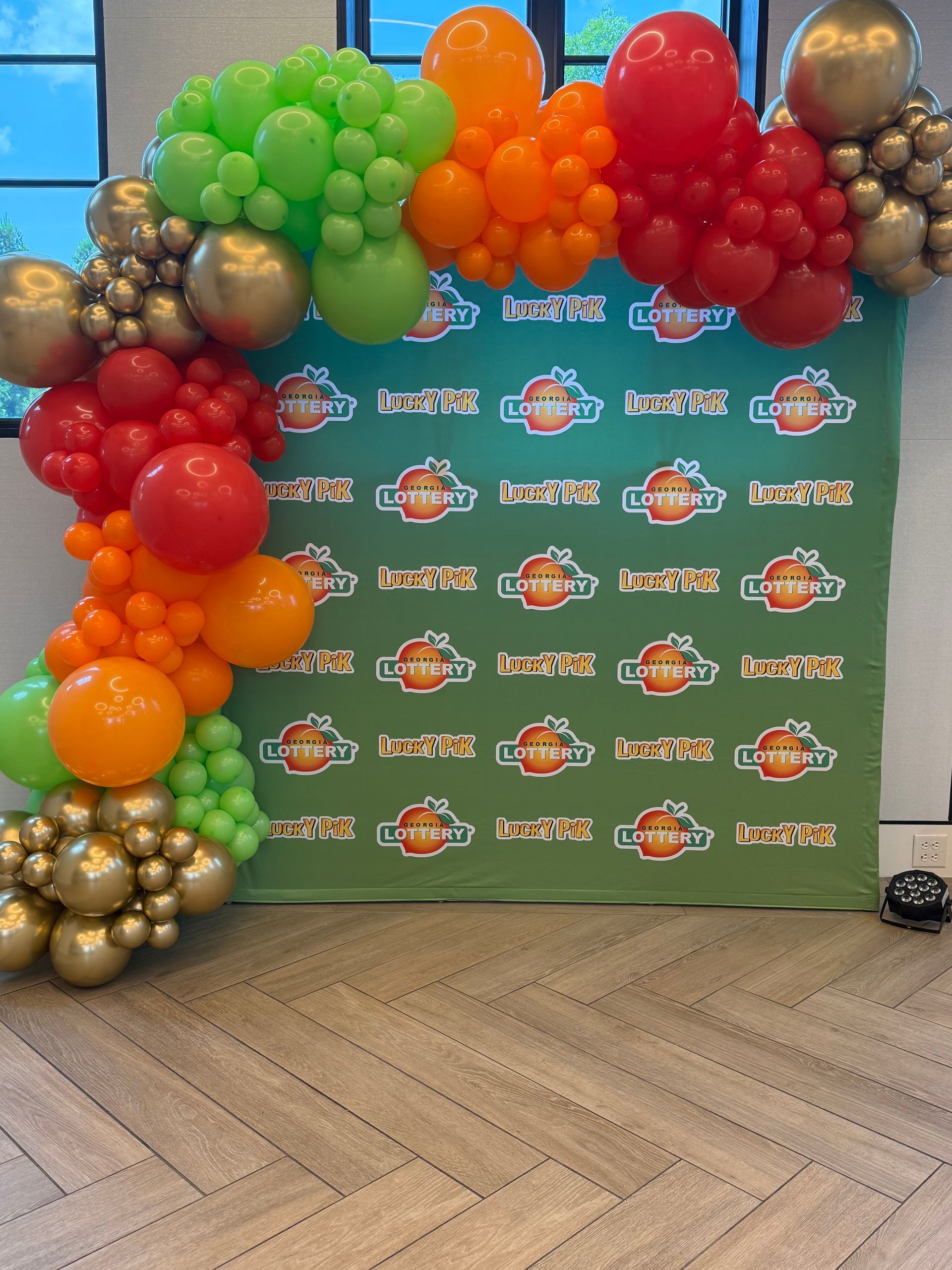 Bright multicolor balloon garland over a branded event backdrop for a promotional display