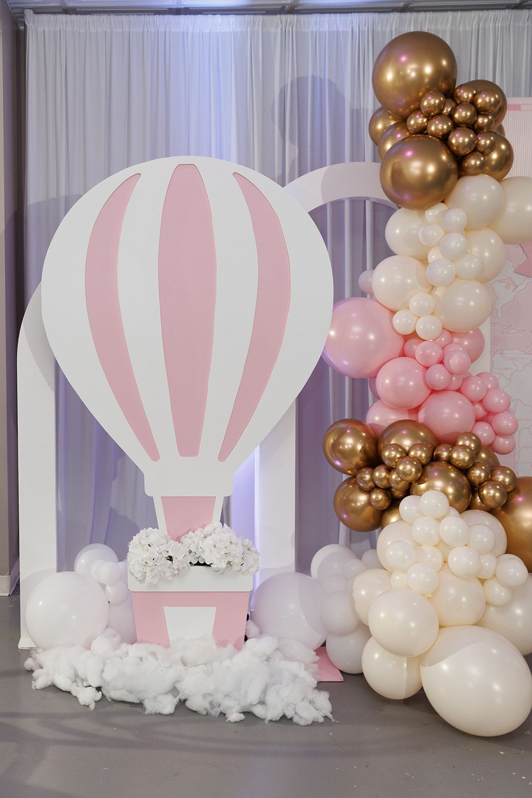 Blush pink and gold balloon cluster backdrop with white draping for baby shower or birthday party