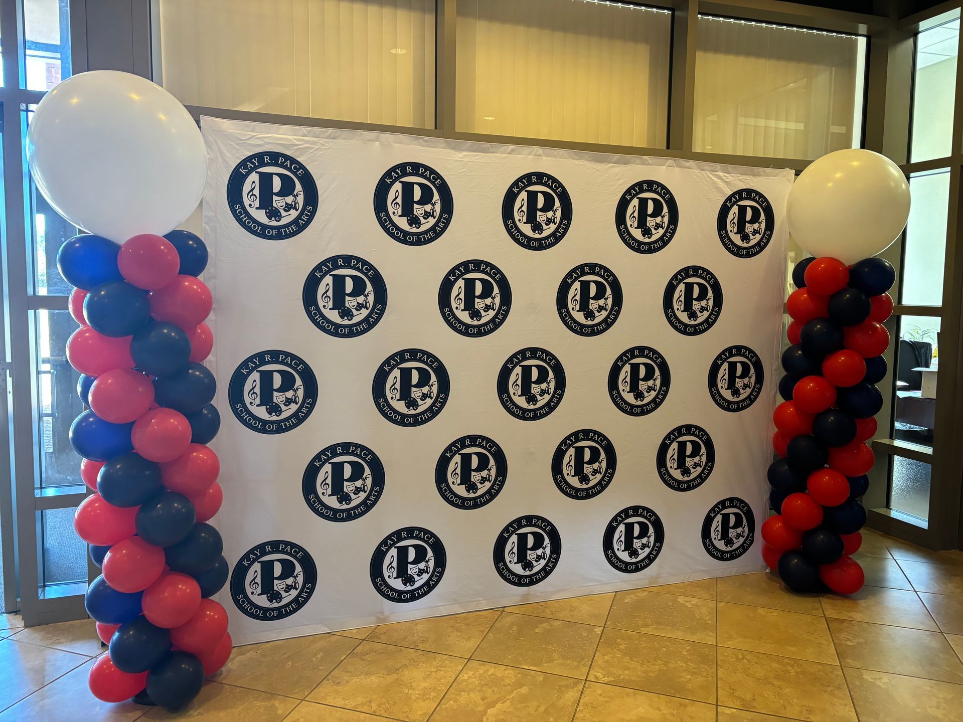Balloon columns framing a branded step-and-repeat backdrop for photos at an event