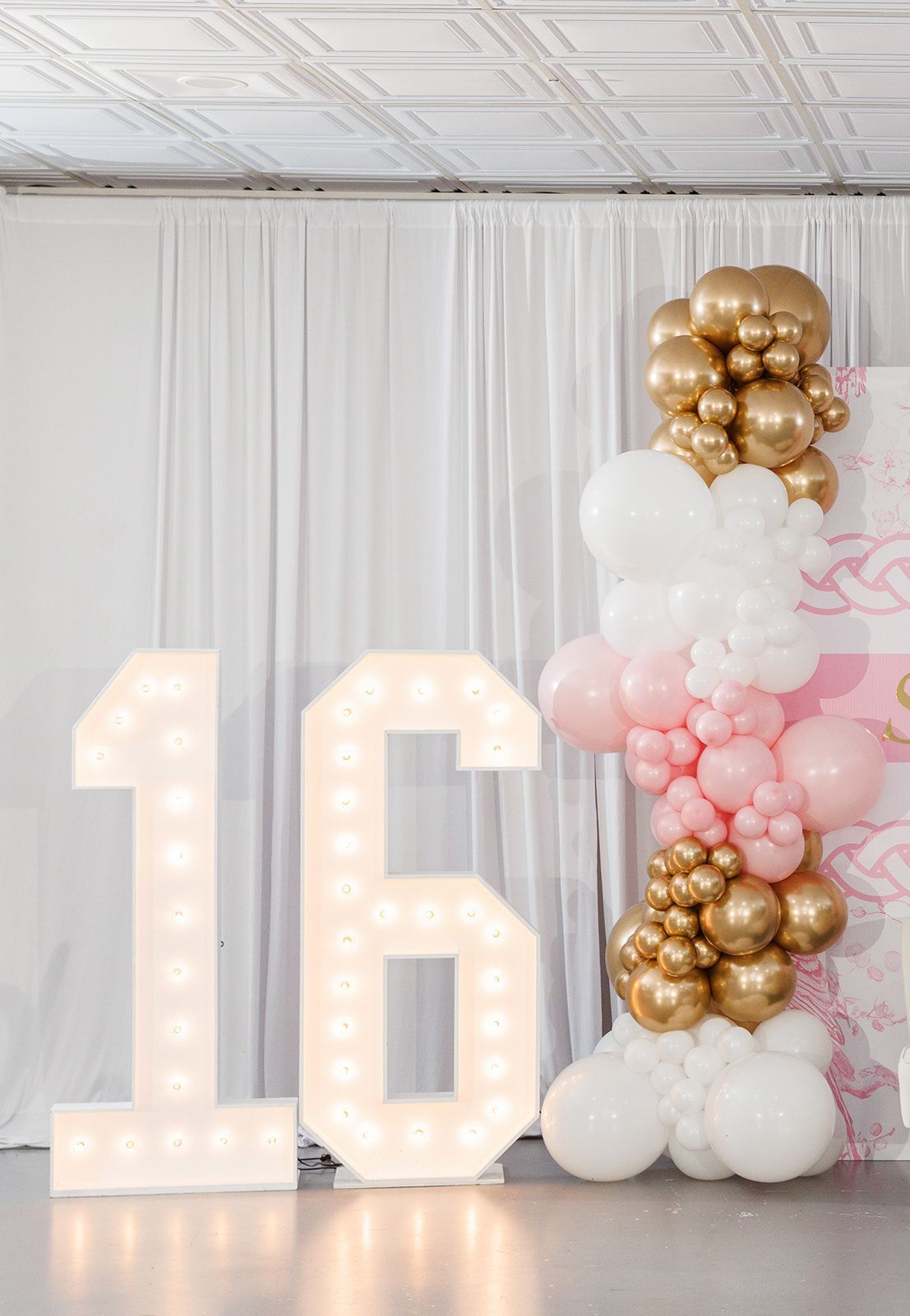 Gold and white balloon garland accent on soft draped event backdrop