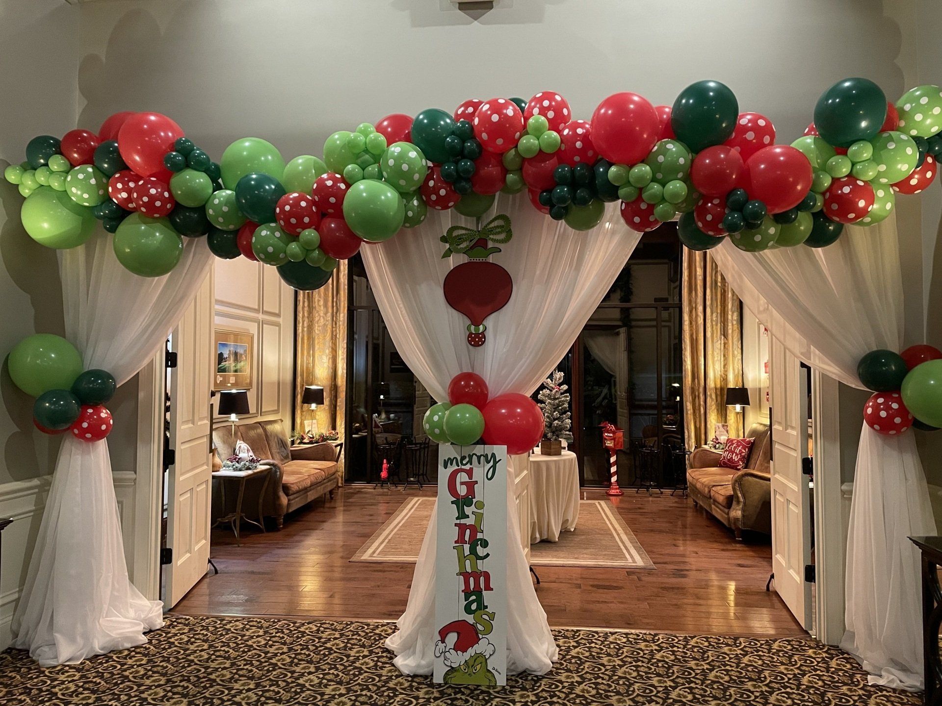 Christmas themed balloon garland in red green and white draped across indoor holiday event entrance