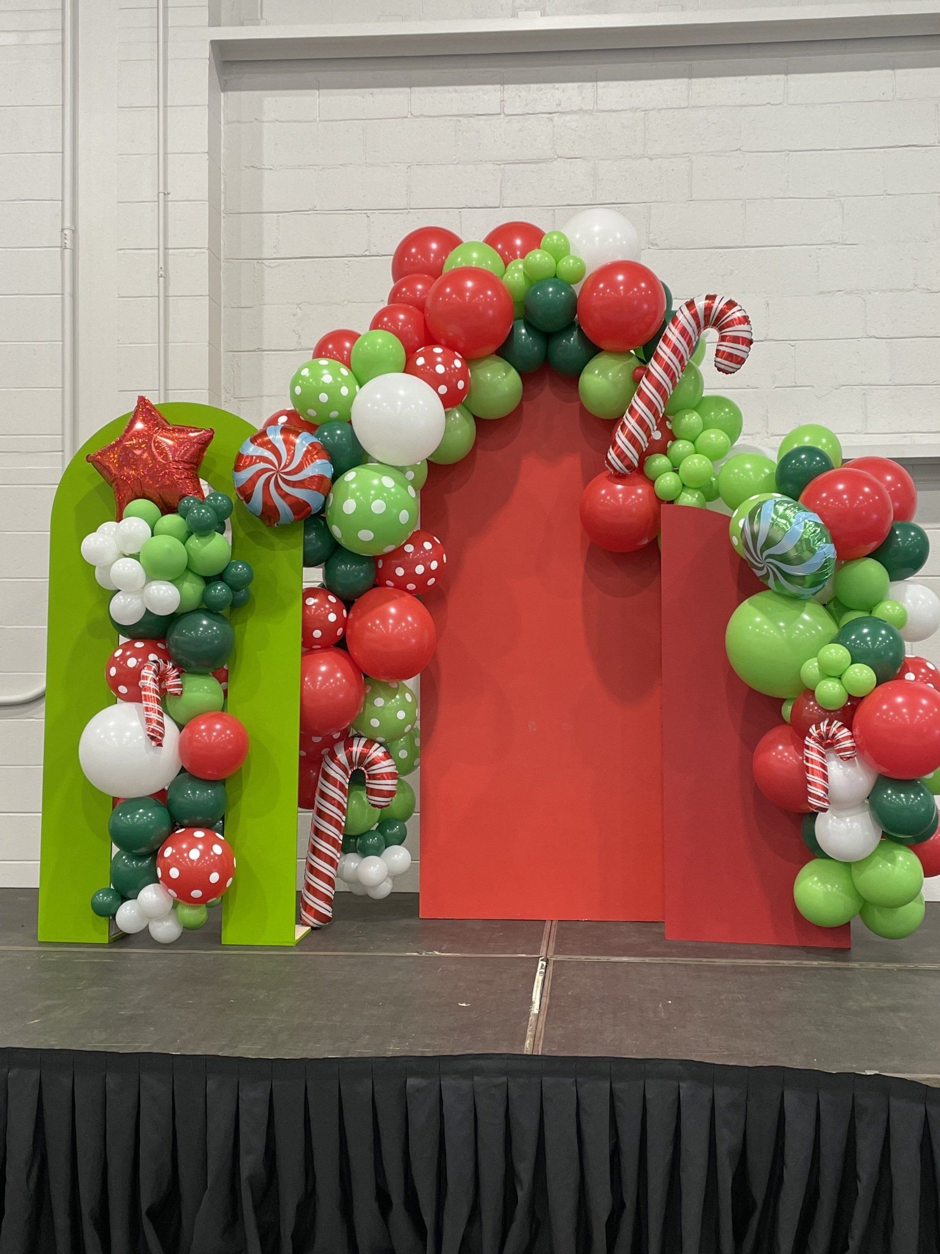 Christmas themed balloon arch in red green and white with candy cane accents for holiday party