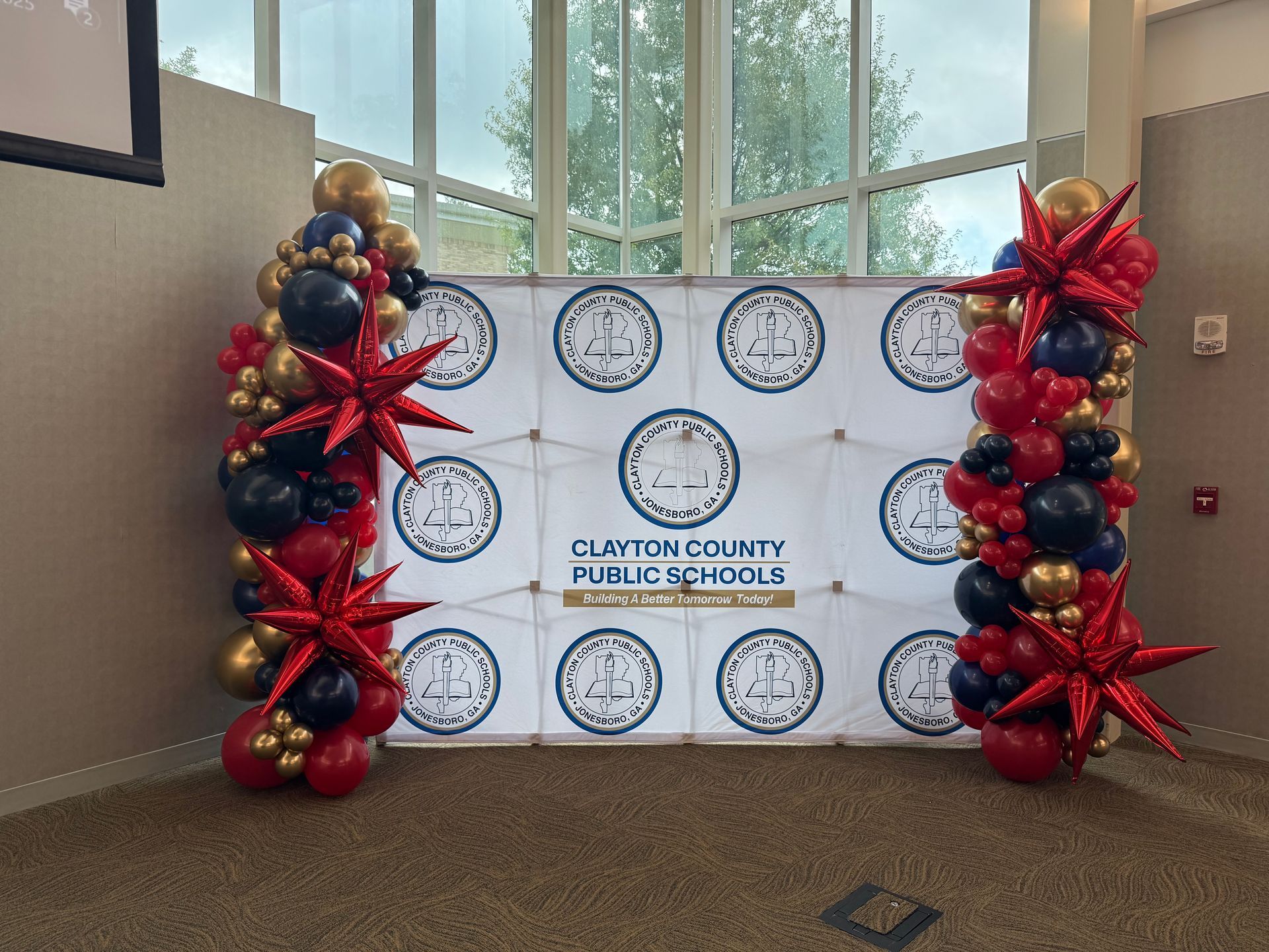 Red black and gold balloon columns framing step and repeat backdrop for school or corporate event in Fayetteville GA